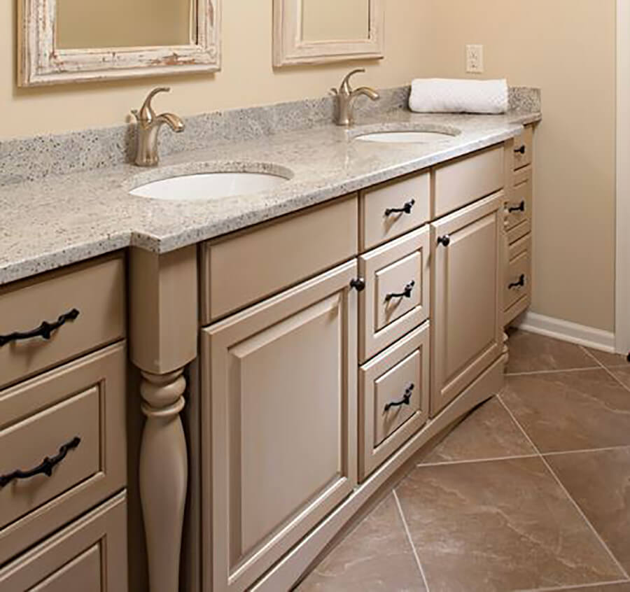 A beige bathroom vanity with a mix of slab drawer fronts for the top drawer and 5-piece drawers for the rest.