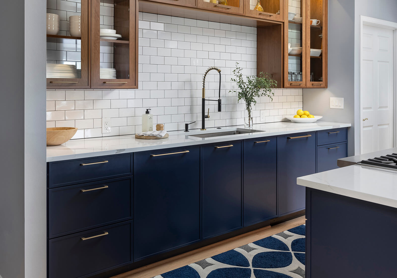 A navy blue and warm wood kitchen design with a hidden panel ready dishwasher with a skinny shaker door style for the appliance panel.