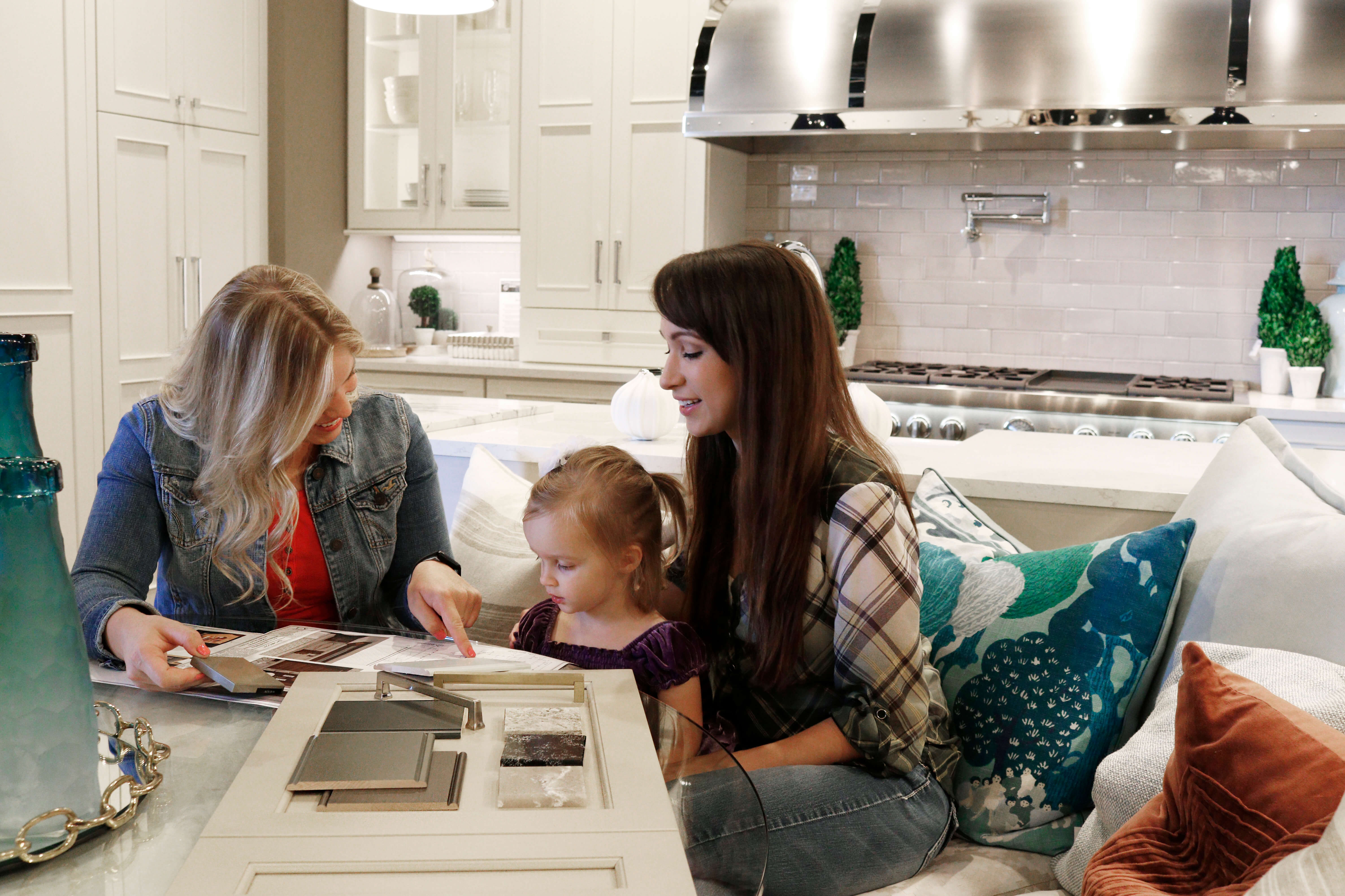 A mother and her child meeting with a Kitchen and Bath designer in a Dura Supreme Cabinetry Showroom.