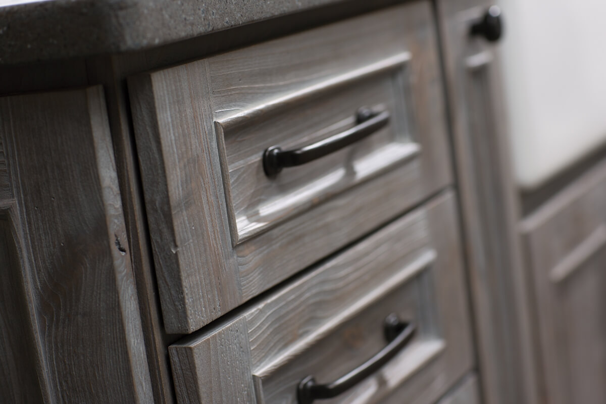 A close up of weathered wood cabinets that look like drifwood and aged barnplanks. Cabinetry from Dura Supreme Cabinetry.