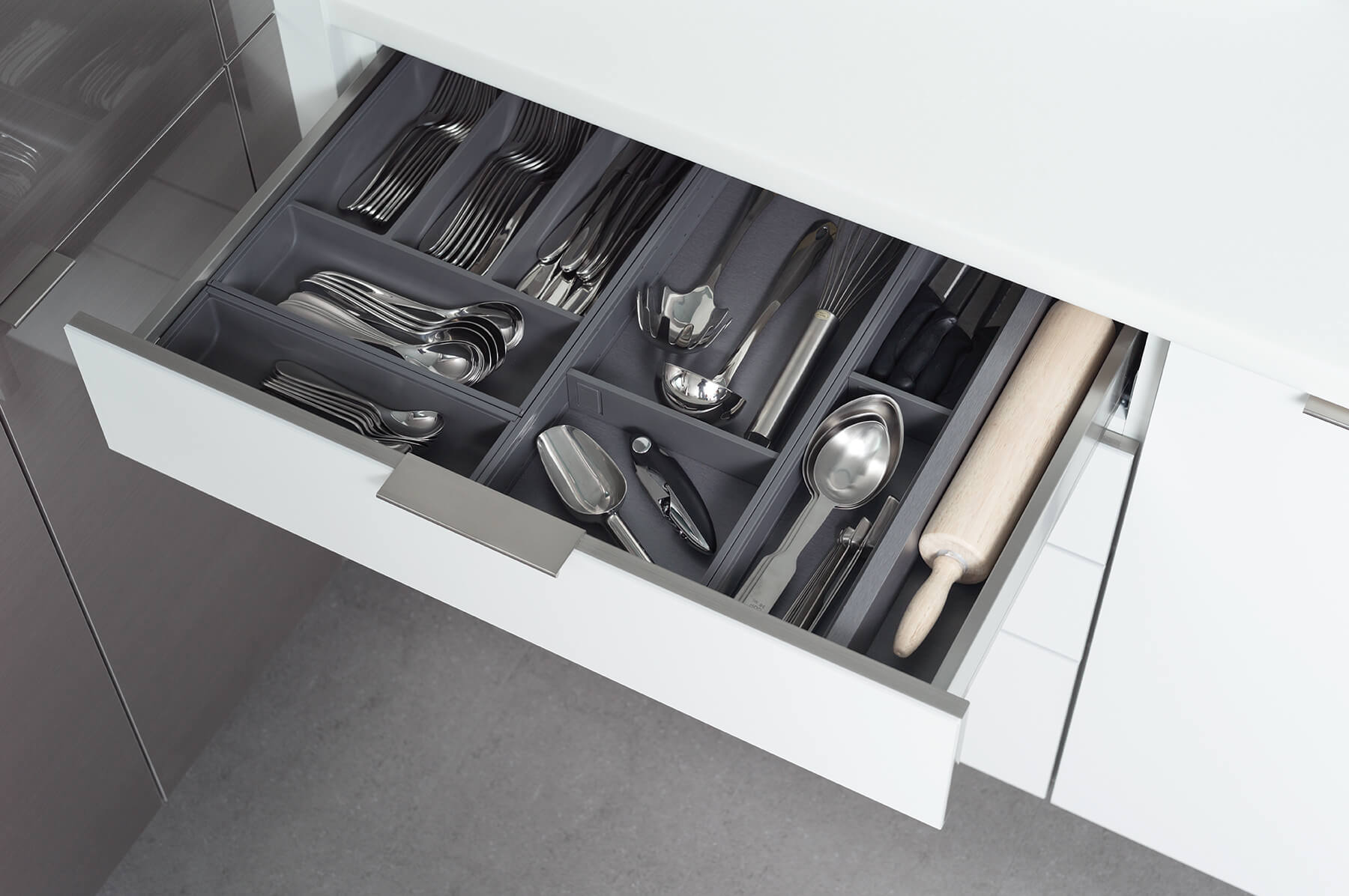A sleek stainless steel drawer for Dura Supreme kitchen cabinets with metal dividers and organizers for utensil storage and misc. kitchen storage.