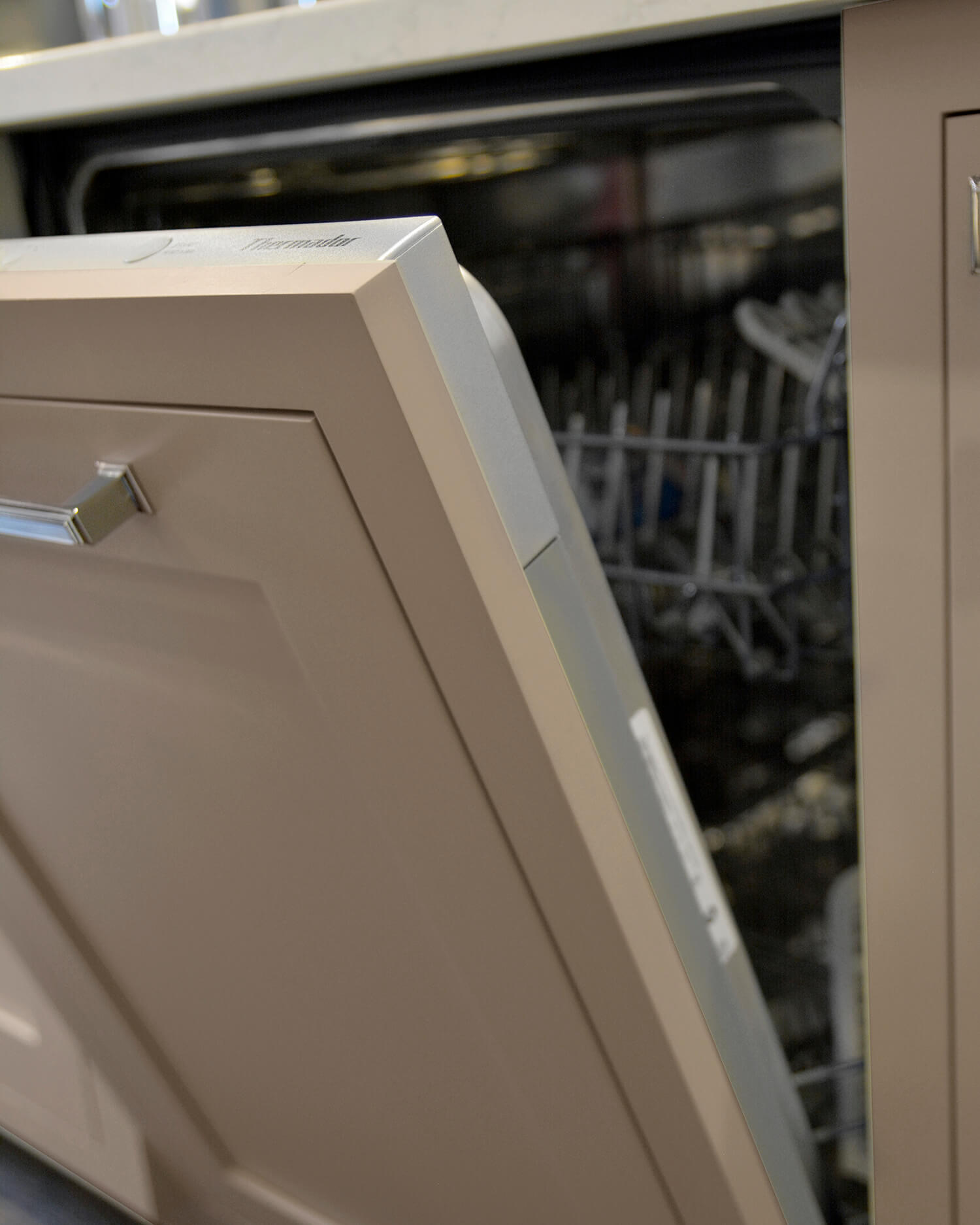 A dishwasher with an inset styled appliance panel in a beige paint color and classic shaker style.