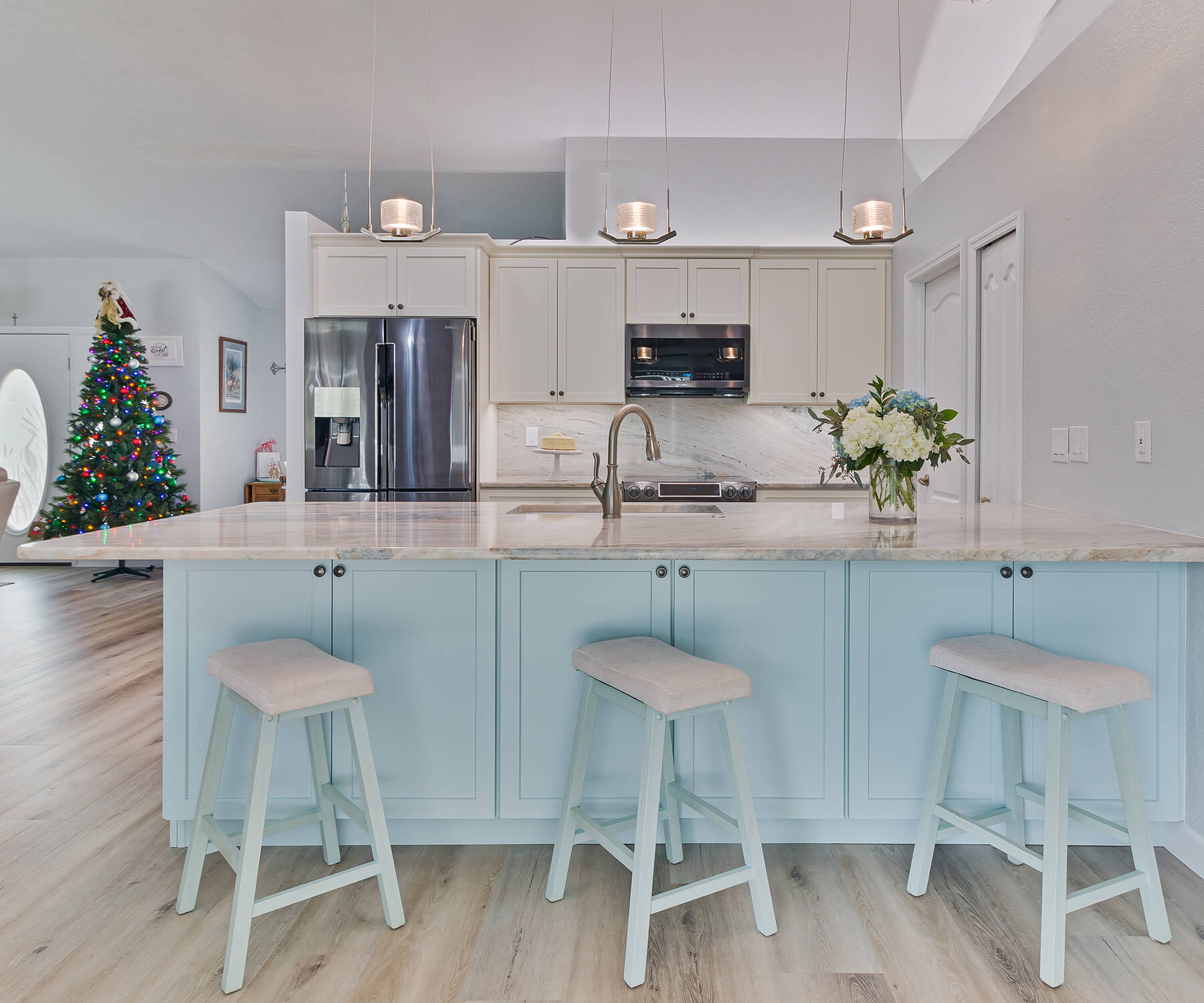 A beautiful white kitchen that is accented by a beautiful, light coastal blue peninsula with breakfast bar seating.