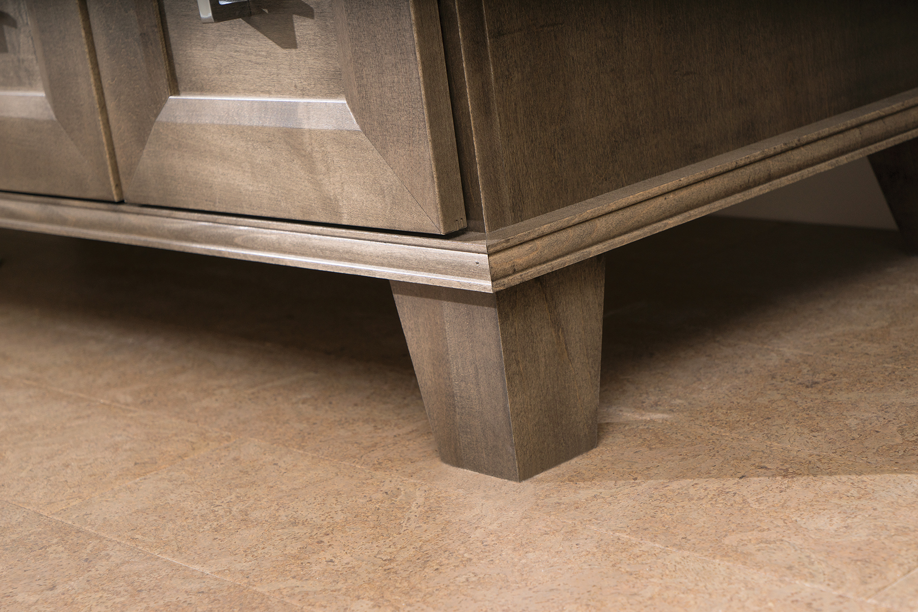 A close up of a furniture style vanity with a transitional styled bun foot detail.