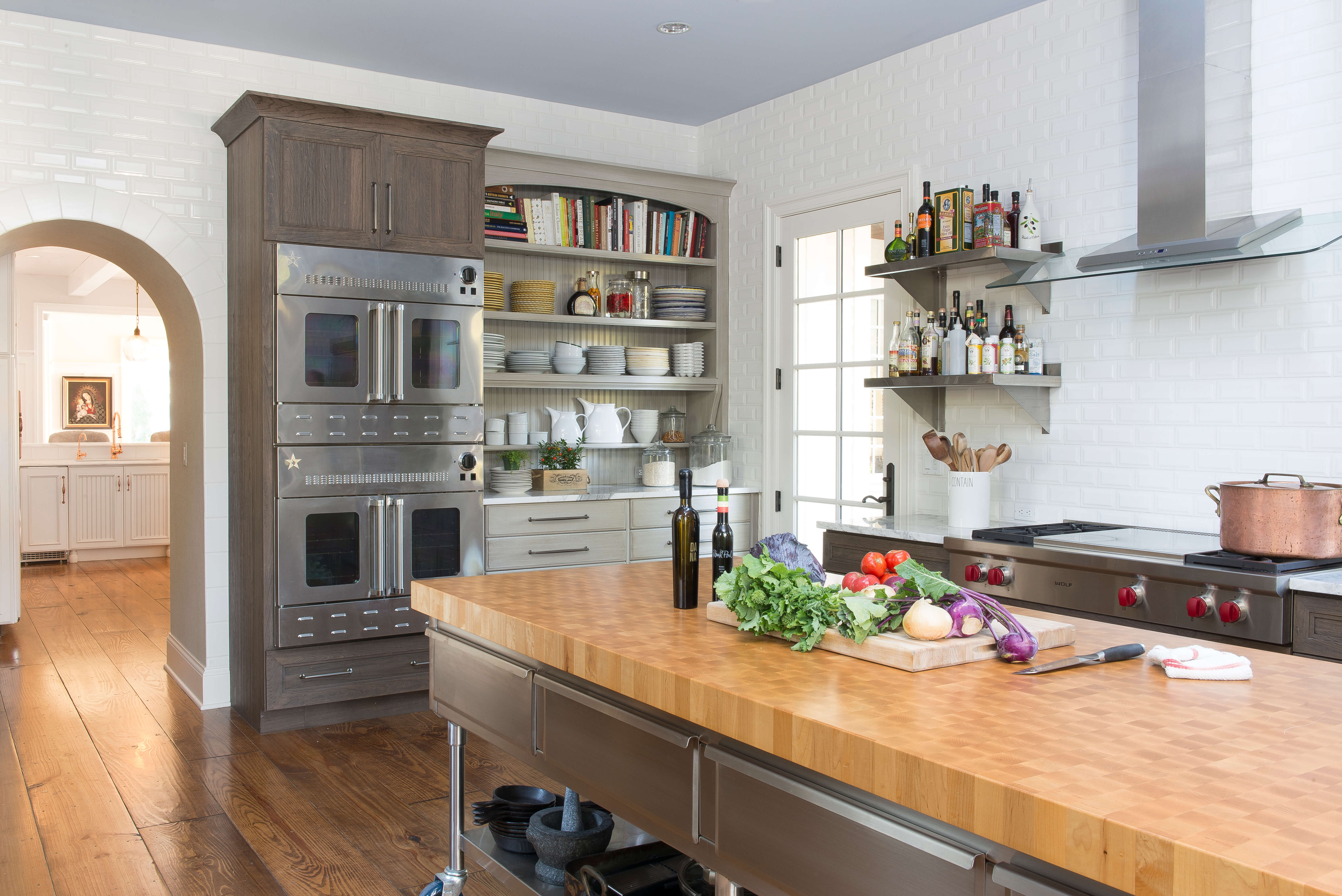 A long island with a butcher block countertop provides a large work service for food prep.