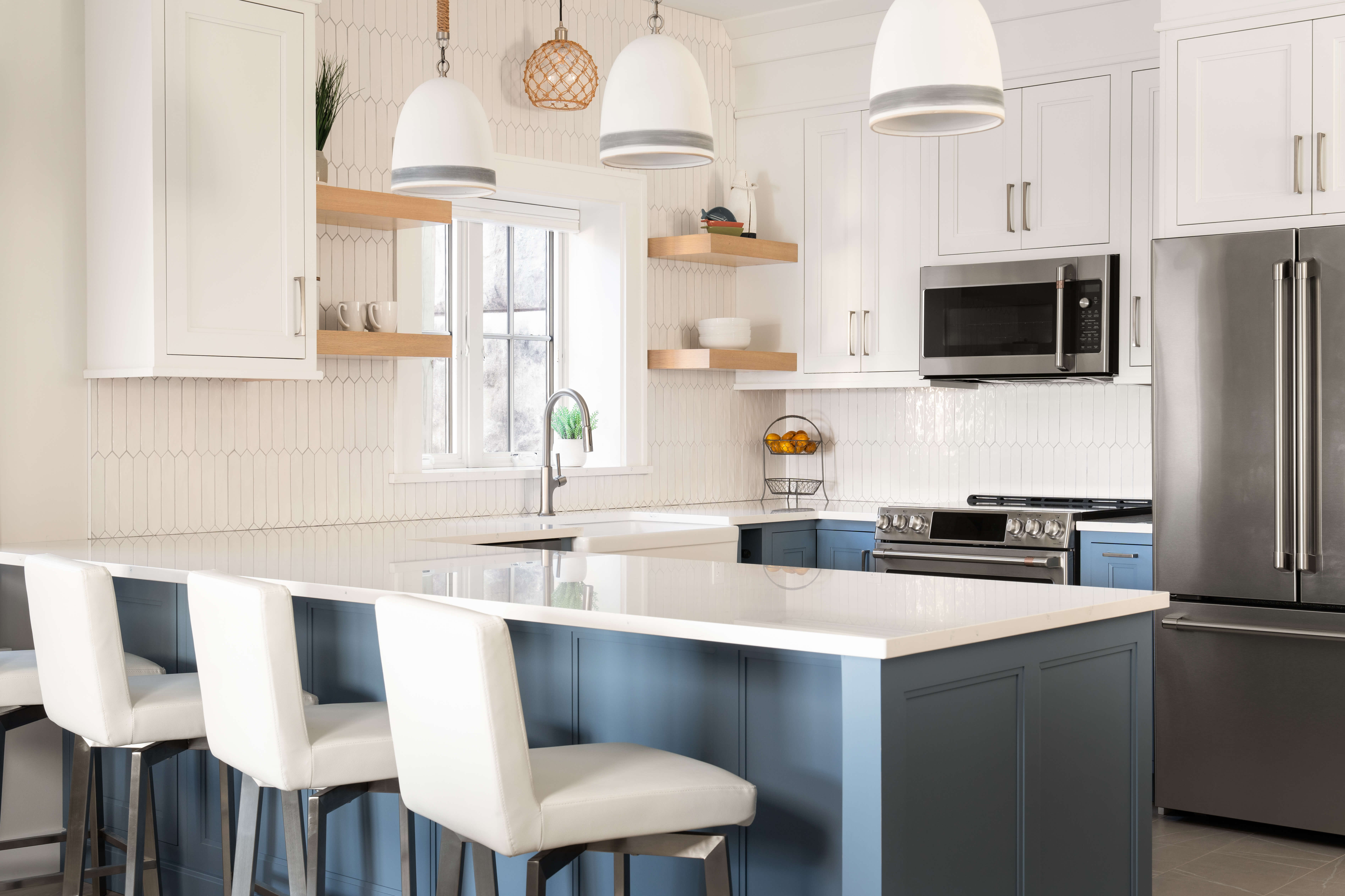 A blue and white kitchen design with a long kitchen peninsula with seating for four people.