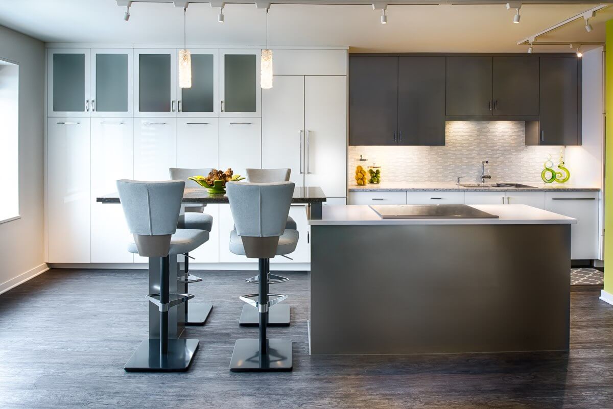 A contemporary kitchen design with gray and white cabinetry and a multi-level kitchen island with bar height stool seating for four.