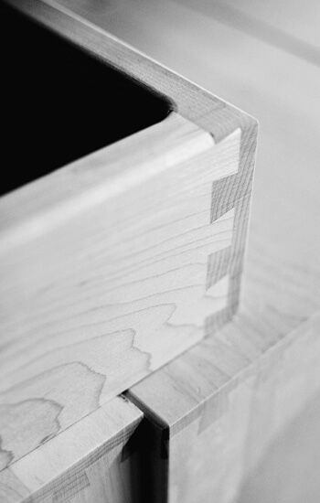 Premium kitchen cabinets with solid joinery and construction. This is a close up of dovetail joinery on a kitchen cabinet drawer shown with black and white photography.