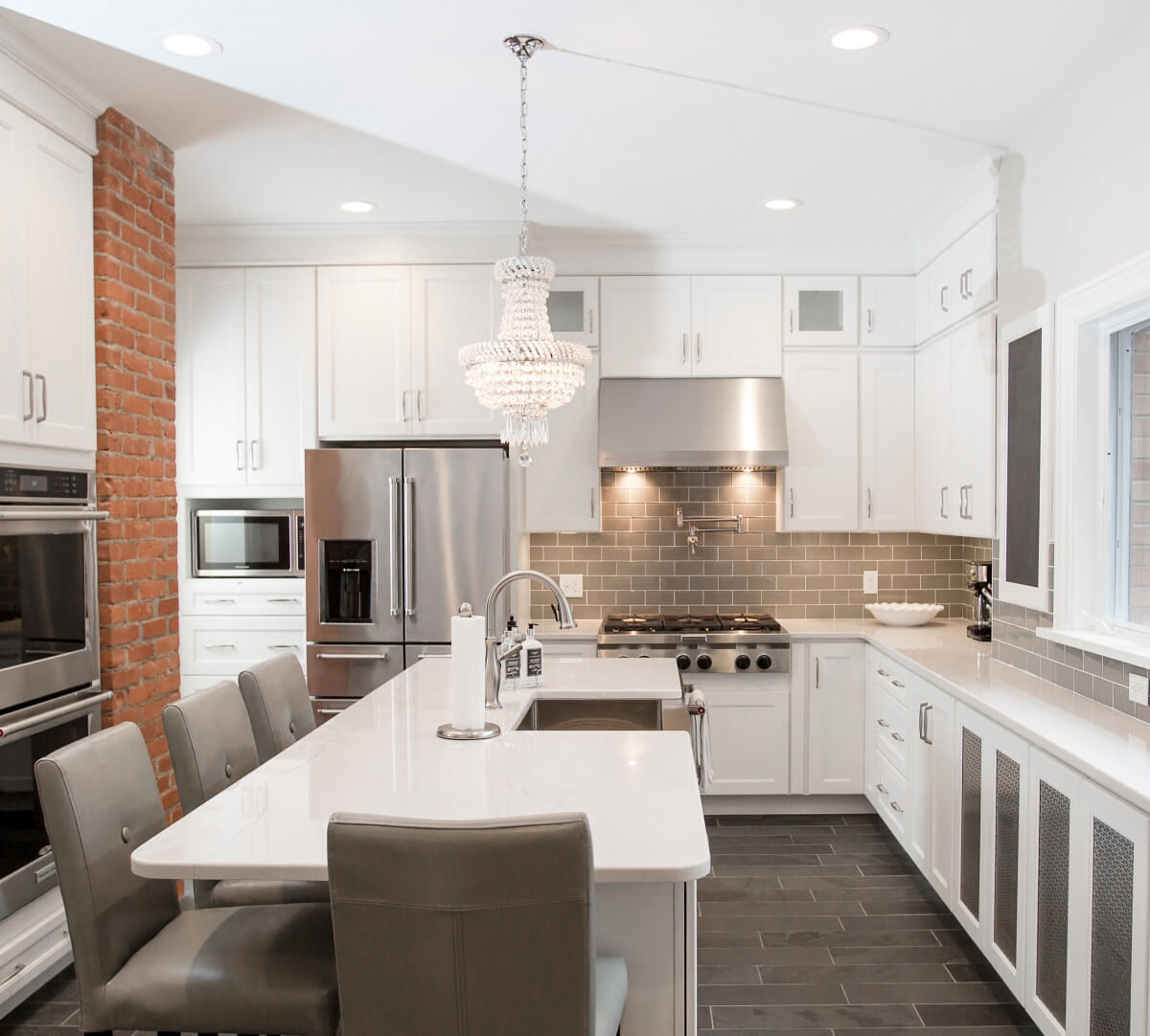 A white on white kitchen with Dura Supreme cabinetry and a large chandalier over the kitchen island.