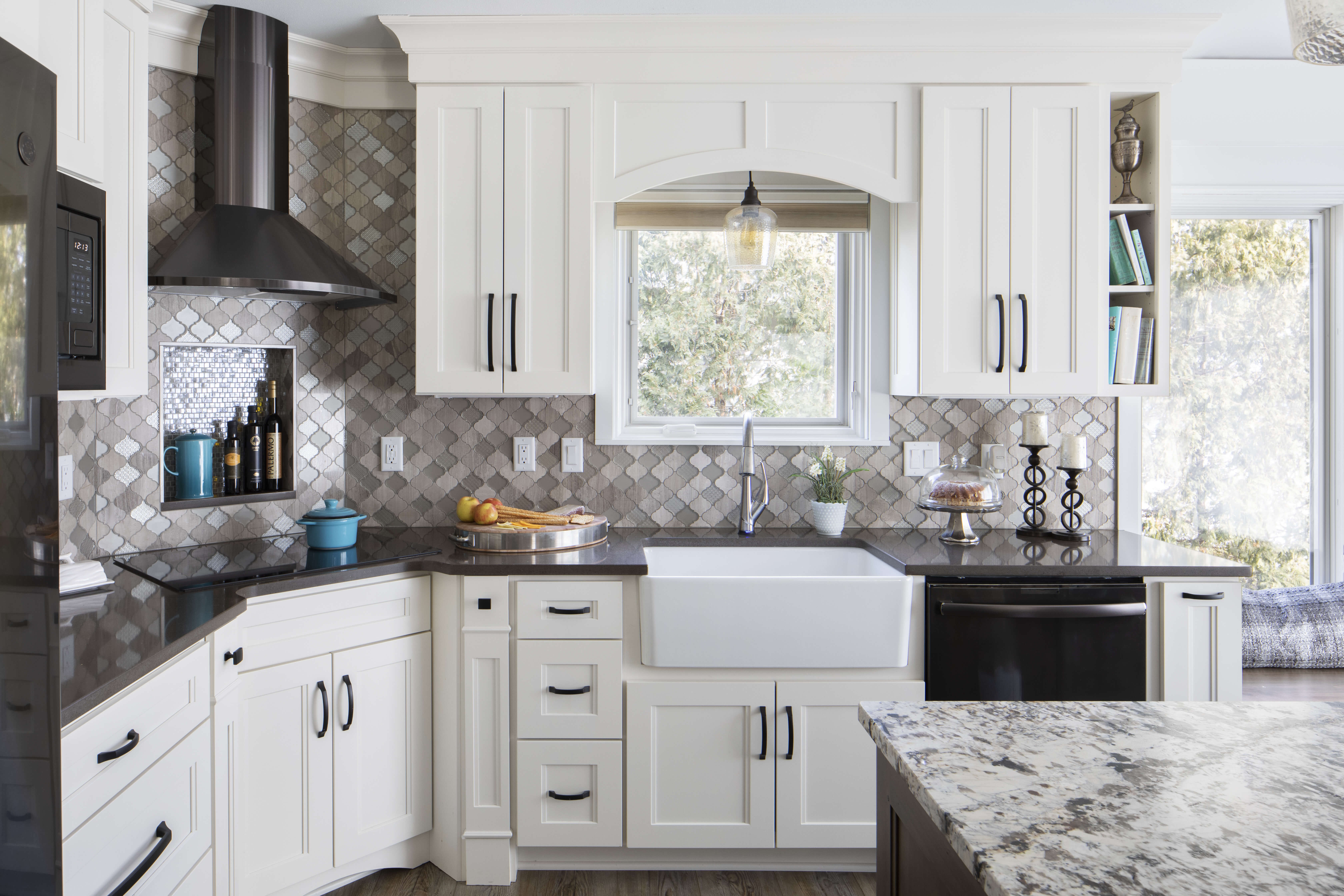 A transitional kitchen with white painted cabinets, black stainless steel appliances and black countertops.