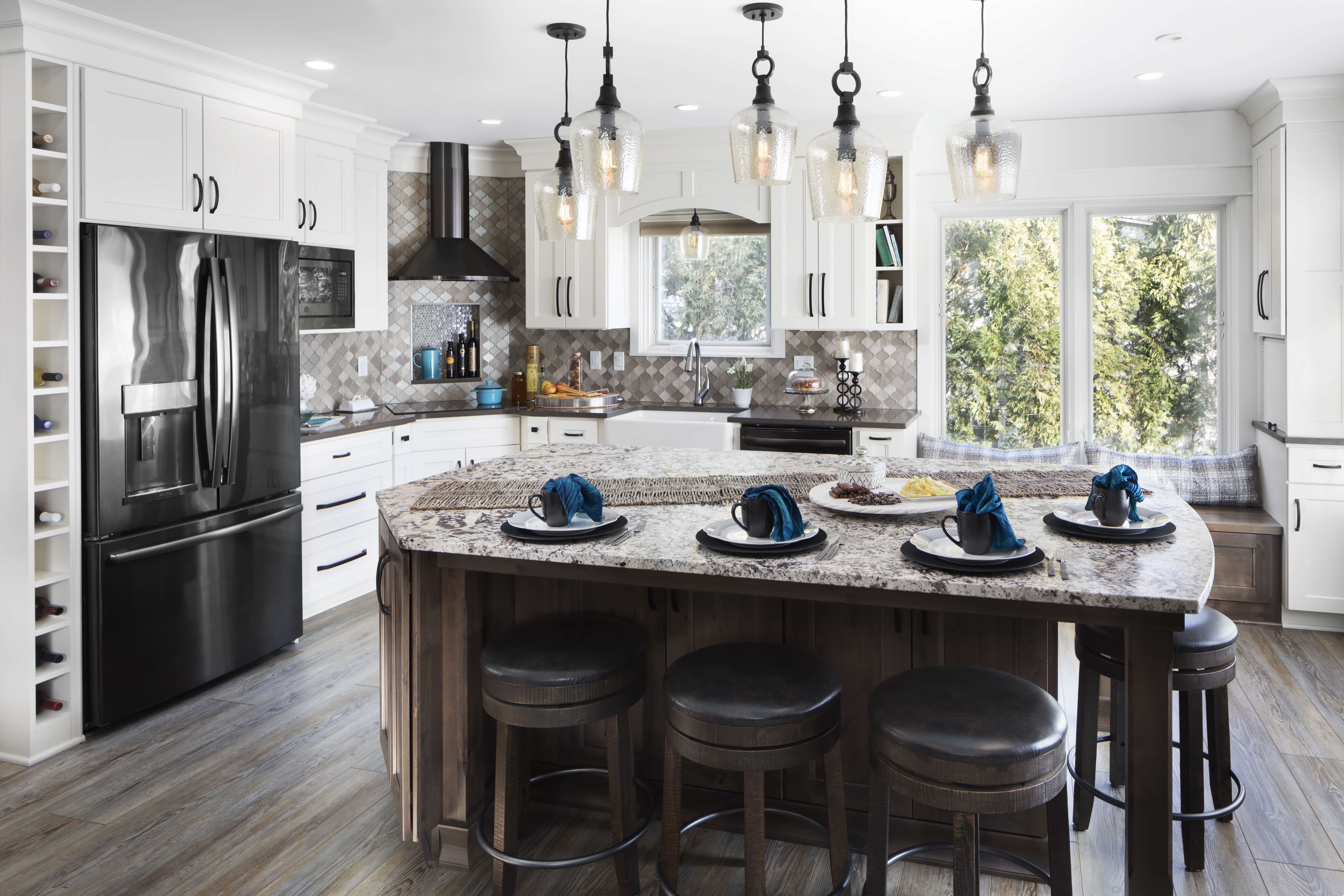 A beautiful lake house kitchen with a modern and casual style. The kitchen has white painted cabinets and a gray stained kitchen island with Knotty Alder wood, a boot bench window seat and lots of personalization.