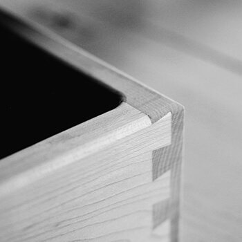 A beautiful close up of dovetail joinery on a kitchen cabinet drawer shown with black and white photography.