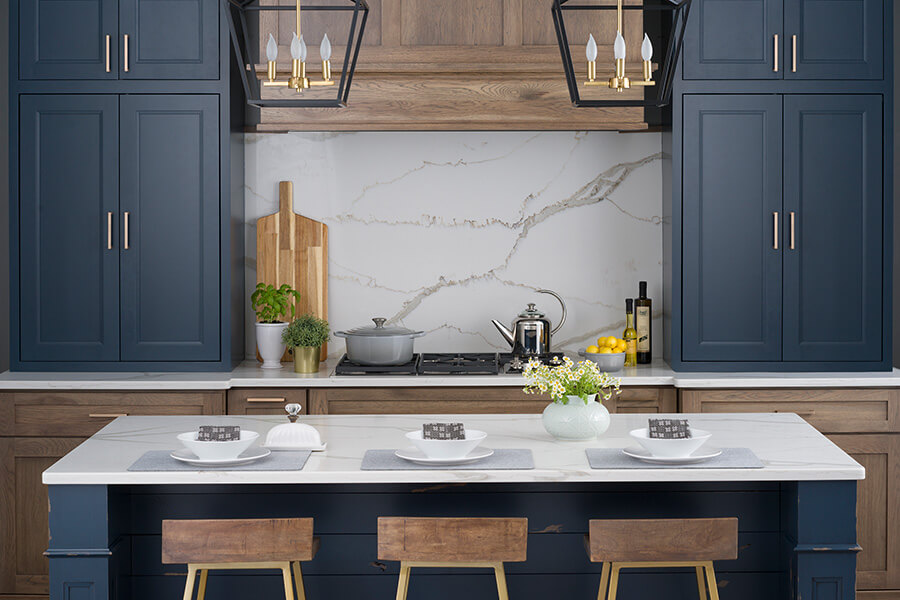 A modern farmhouse kitchen desing witha modern hickory wood hood and base cabinets accented by trendy Navy Blue painted upper cabinets and kitchen island with deep blue shiplap accents.