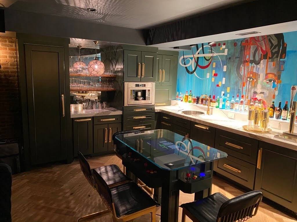 A home bar with dark green cabinets in a basement remodel.