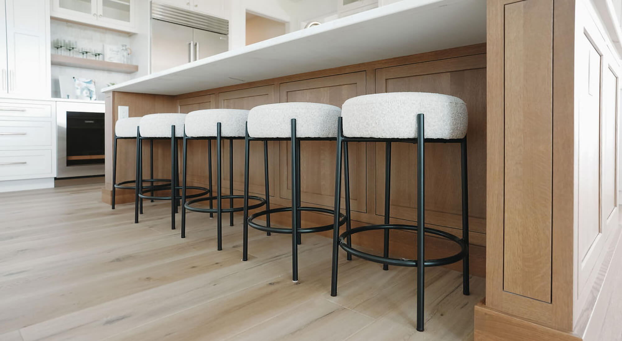 A close up showing under a counter height overhang with kitchen island stool seating for five people.