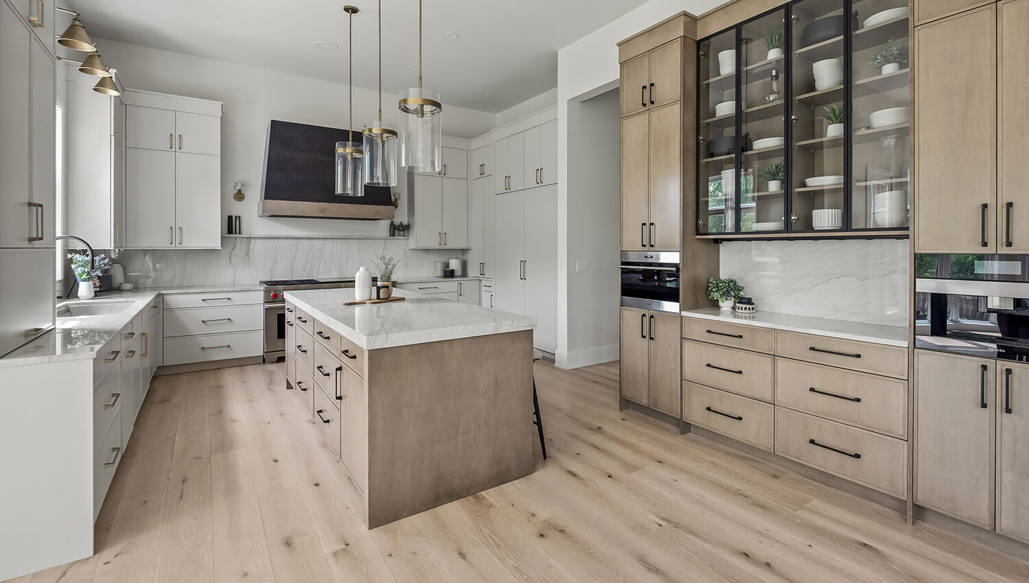 Dura Supreme's Reese skinny shaker door style in Canvas paint for the perimeter, the Cashew stain on Maple for the island and accents, and the Onyx on Maple for the wood hood and additional accents.