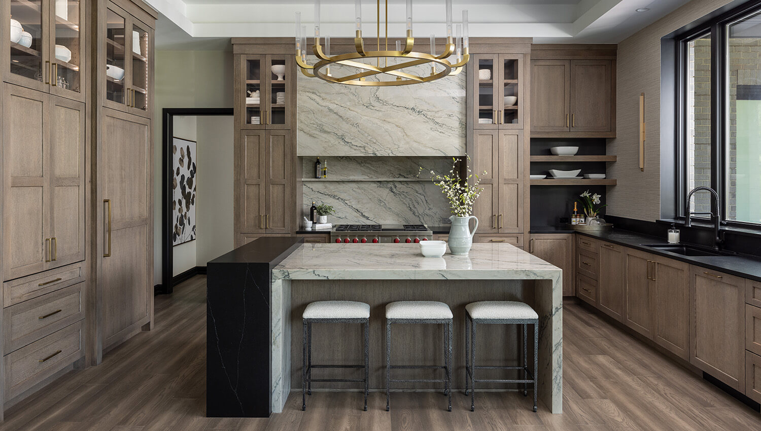 A Modern Prairie styled kitchen design by Sandra Daubenmeyer of KSI Kitchen & Bath, Michigan. The cabinets feature Dura Supreme's Carson door style in the Morel stain on Quarter-Sawn White Oak with accents of the Onyx stain on Maple. 