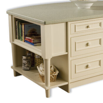 An open kitchen island end cap with open shelf storage at the top with a floor shelf below and two decorative furniture style turned posts with a table-like look in an off-white paint.