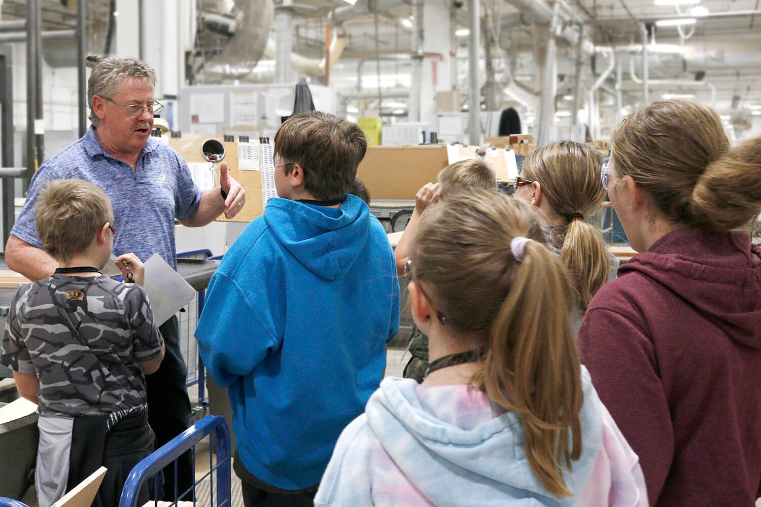 A manufacturing safety manager giving a tour to kids to teach them about cabinet making and the wood working industry.