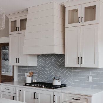 A modern wood hood with shiplap paneling in a white painted kitchen.