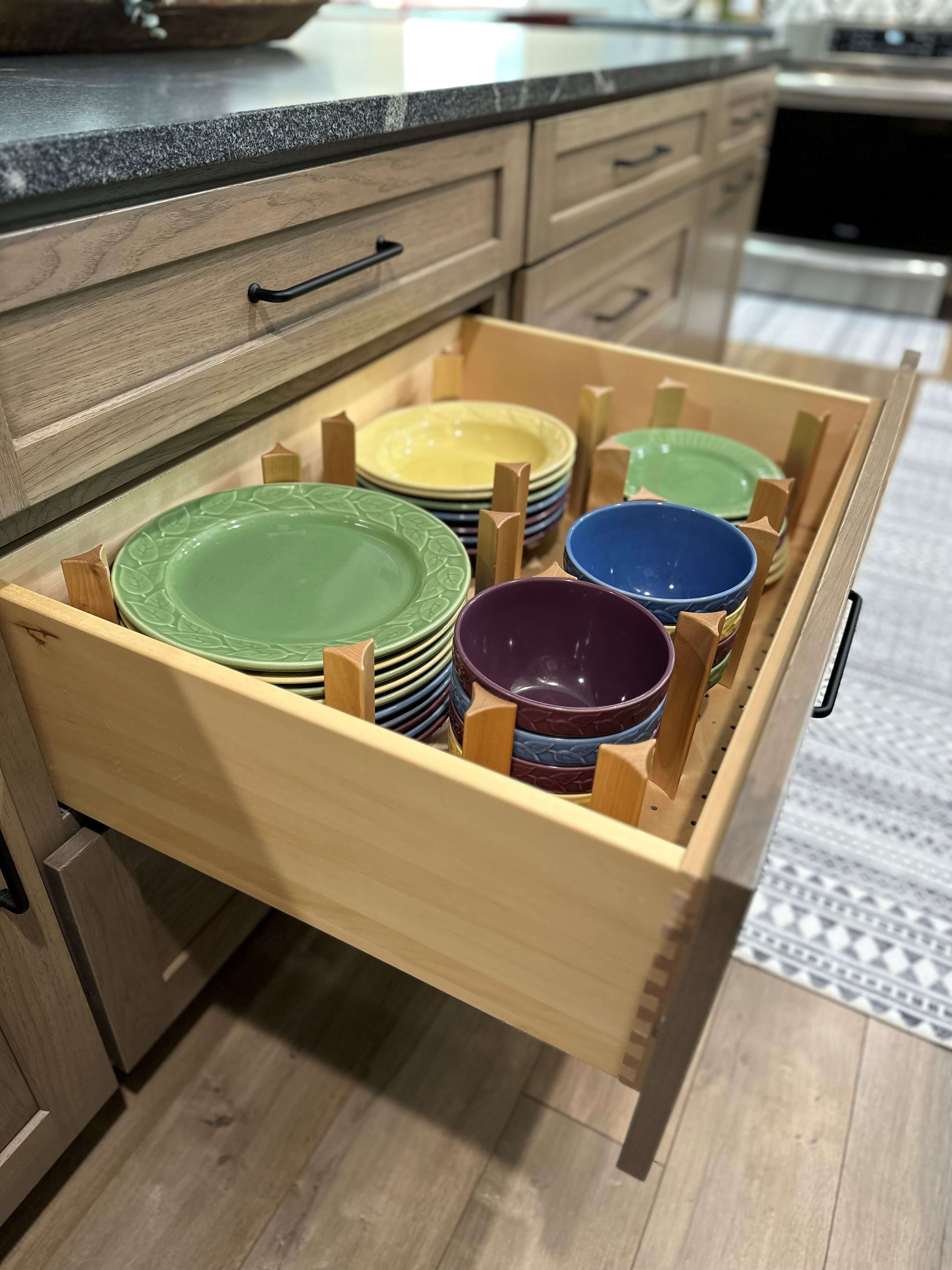 A deep drawer in the kitchen island organizes and securly stores a full collection of dishes and bowls.