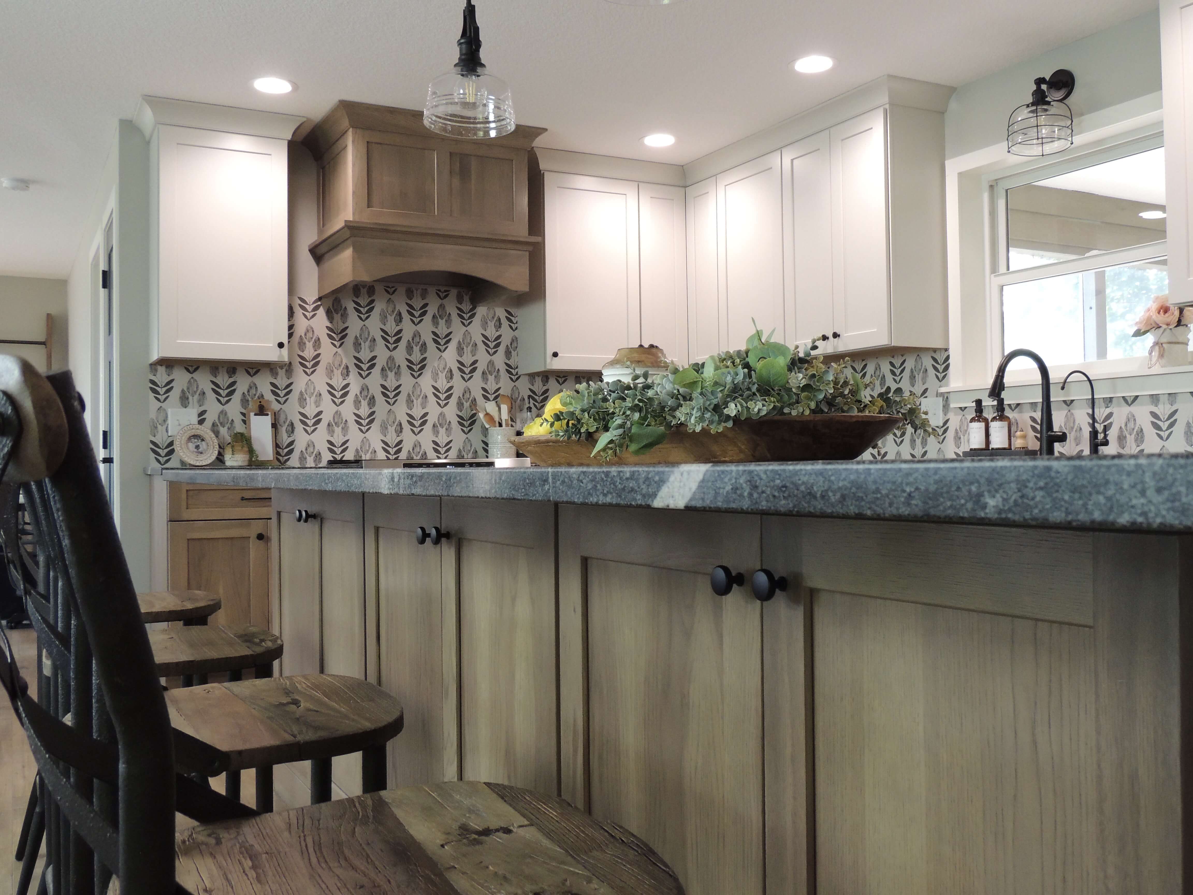 A view of the new remodeled kitchen from the kitchen island showing the contrasting wood hood and wall cabinets.