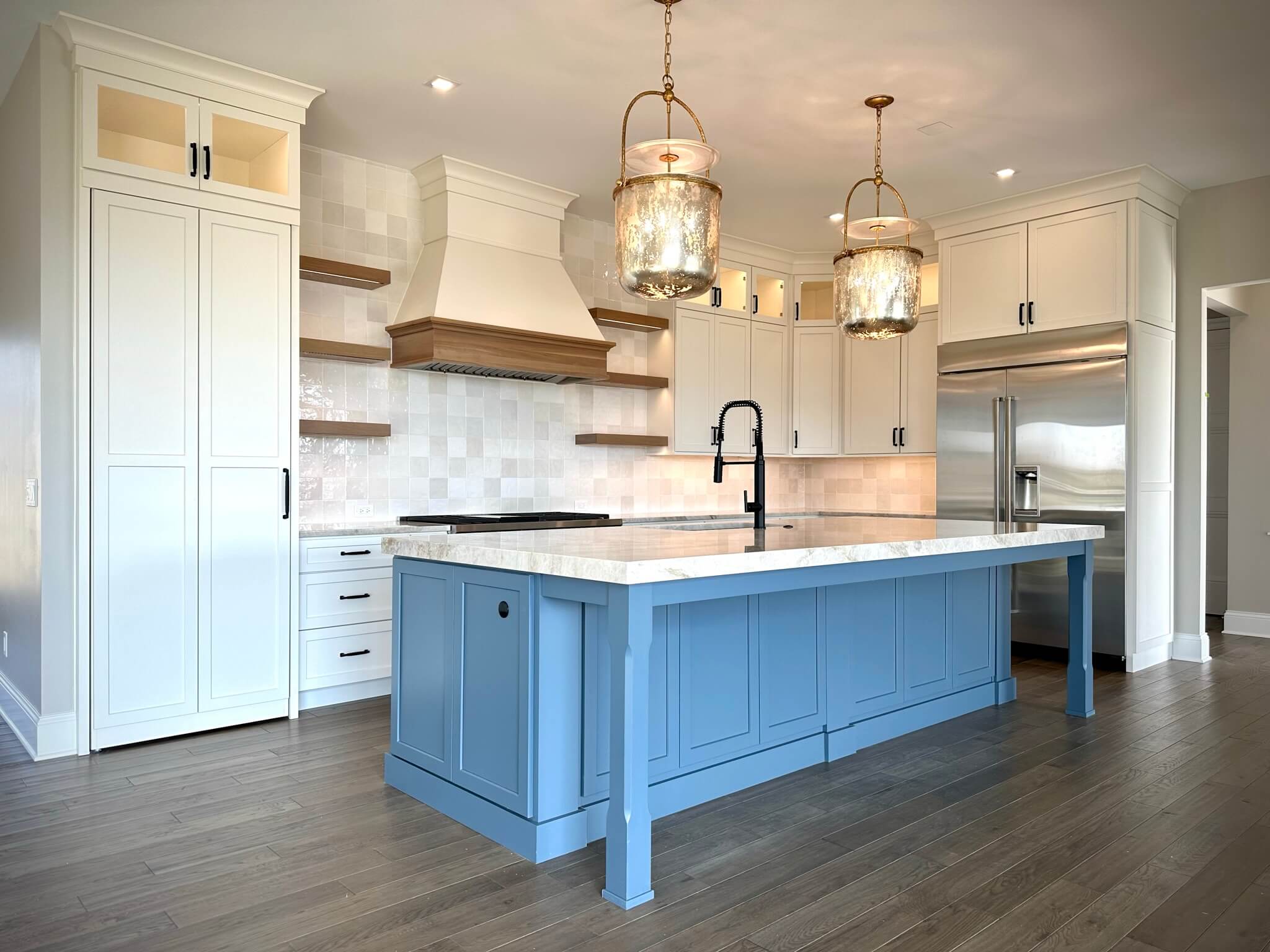 A beautiful and inspiring white and gray kitchen with light wood accents. The white painted cabinets feature a soft, muted color that's more casual and comfortable then bright white cabinets.