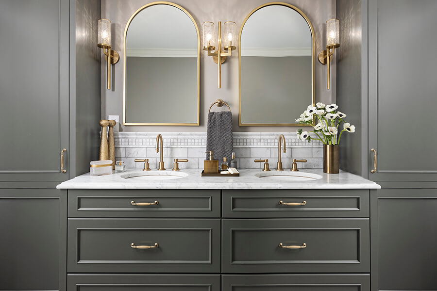 A luxury bathroom design with a traditional styled bathroom vanity with a dark olive green paint color and gold hardware.