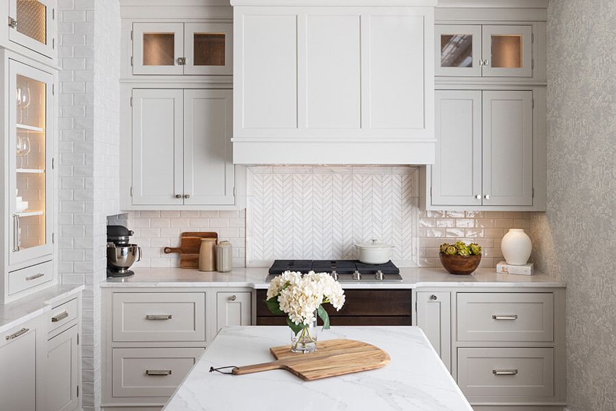 An all white traditional style kitchen design with white painted inset cabinets and a wood hood in a small floorplan of a historic home.