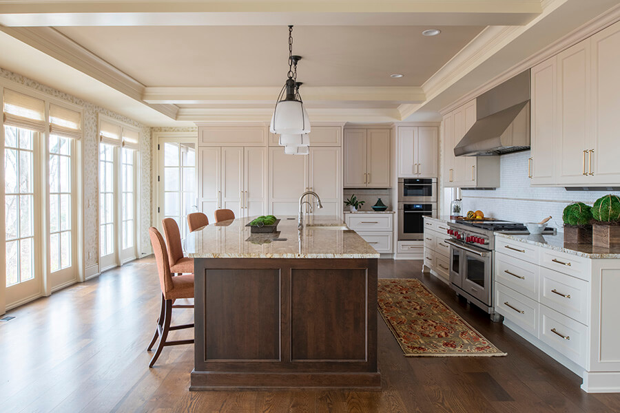A classic traditionally styled L-shaped kitchen design with white painted cabinets and a cherry wood stained kitchen island.