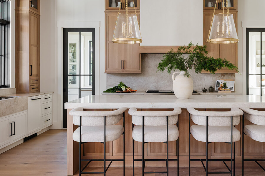 A luxurious and trendy two-tone kitchen with off-white painted and a light stained quarter-sawn white oak cabinets with a modern skinny shaker door style and reeded panel accents.