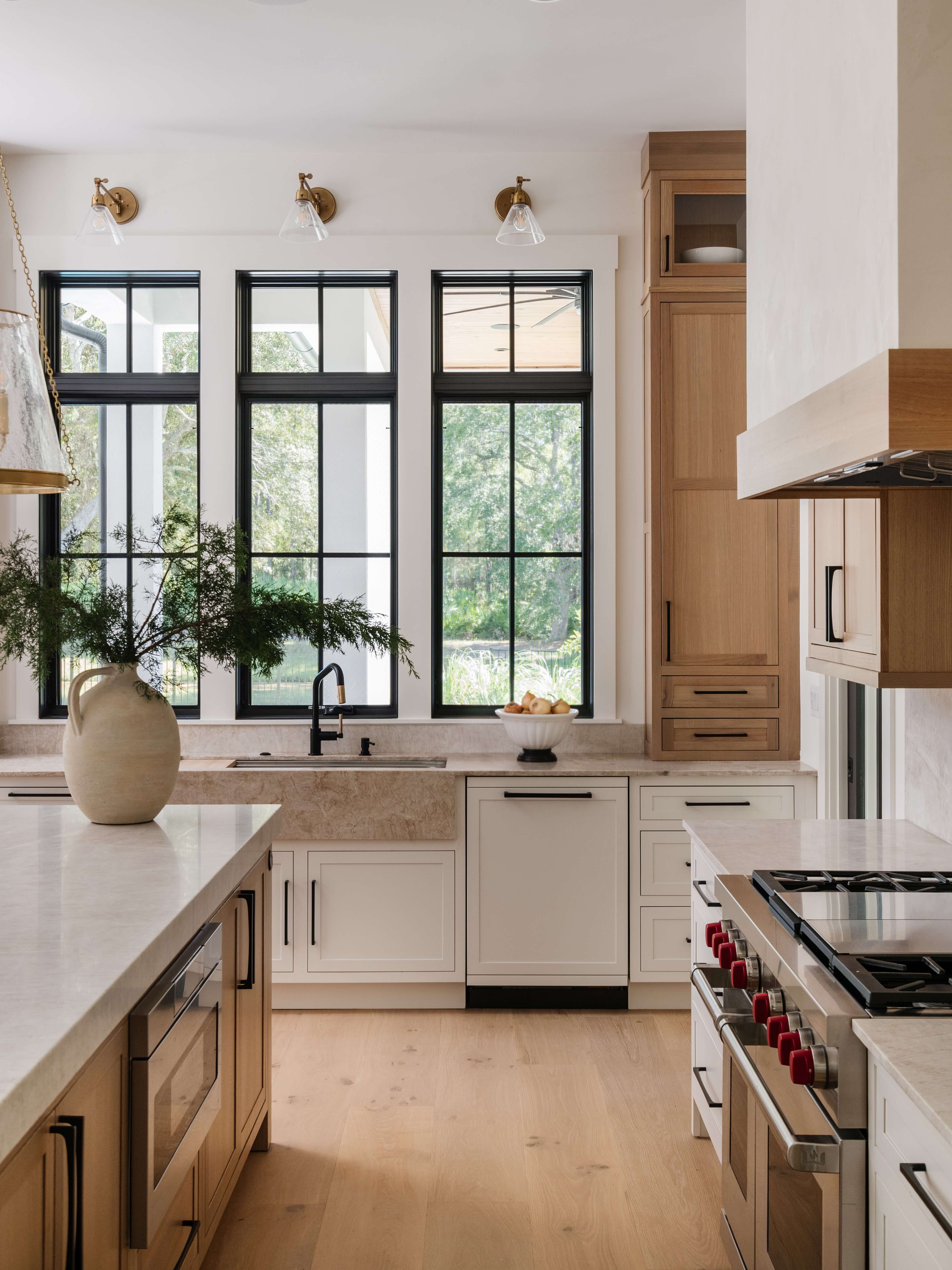A luxurious two-toned kitchen design showing white painted cabinets contrasted by light stained rift sawn, quarter-sawn white oak cabinets using a skinny shaker door style.