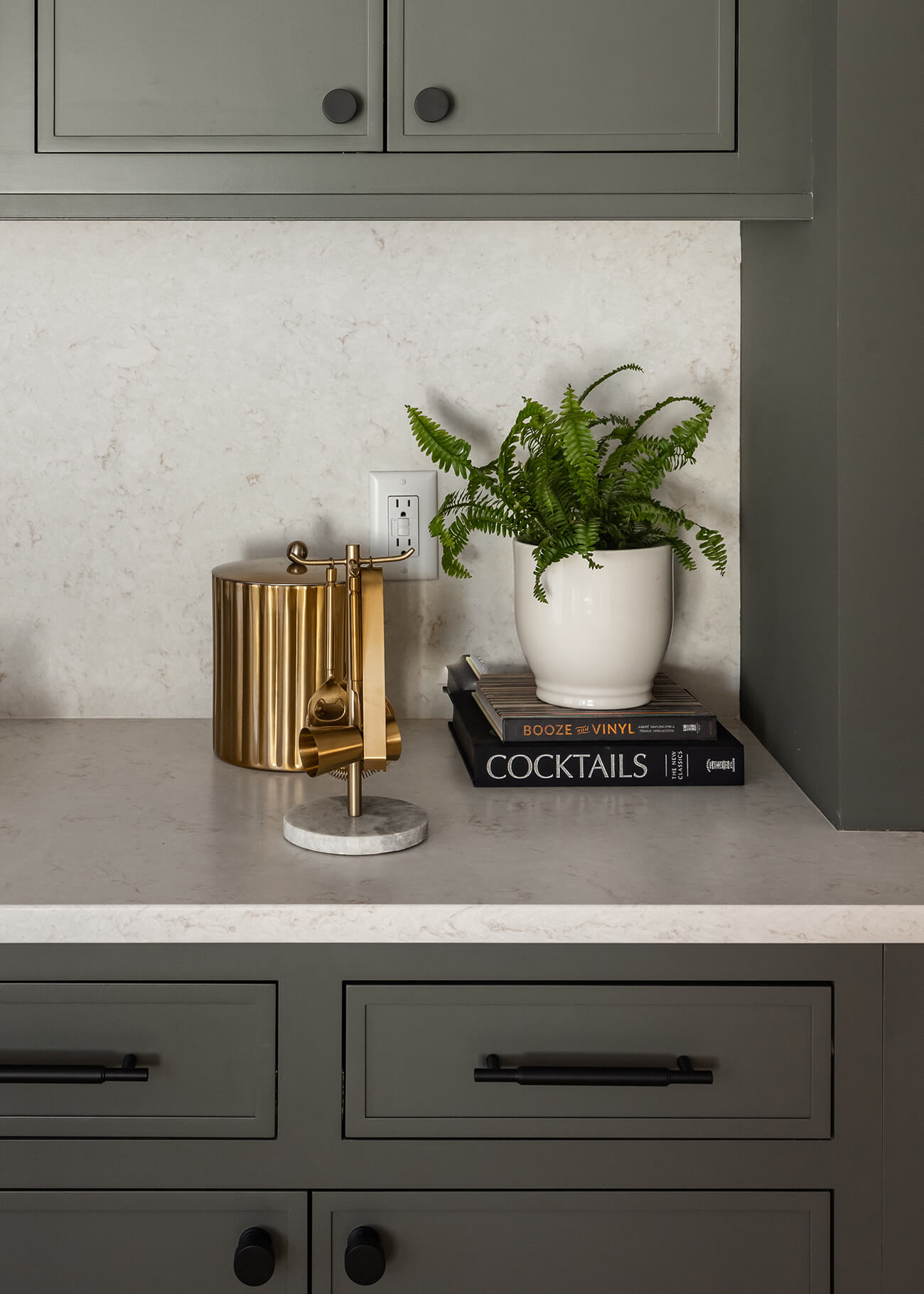 A close up of earthy, sage green cabinets with inset construction featuring a skinny shaker door style in a biophilic styled kitchen design.